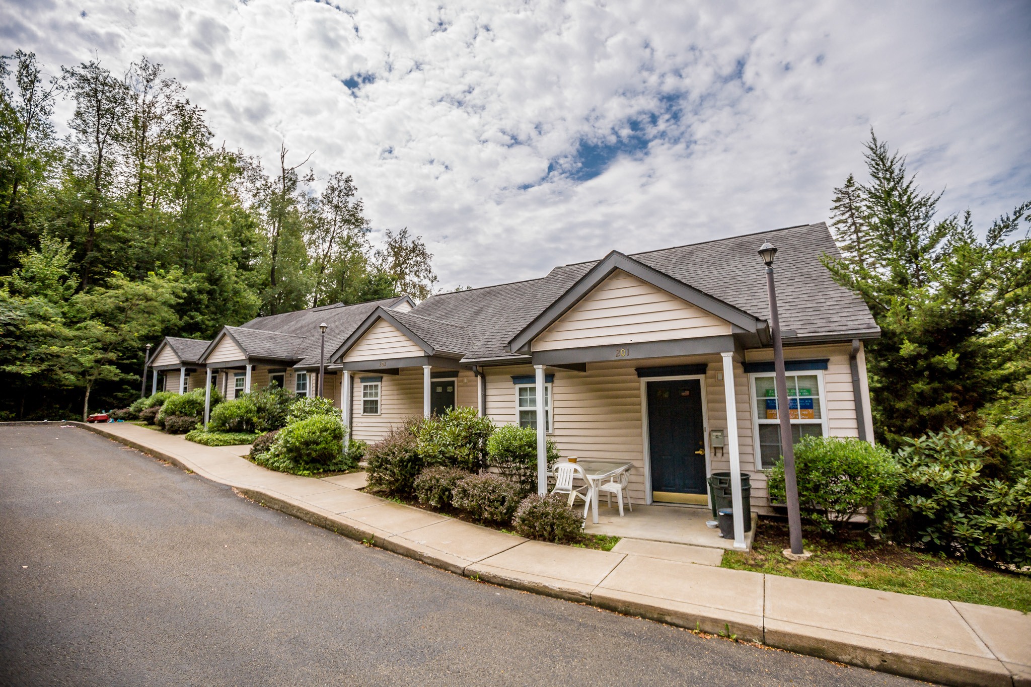 a small house with a porch and a street in front of it